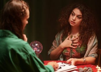 Two women sitting with astrology answers and guidance on the table.